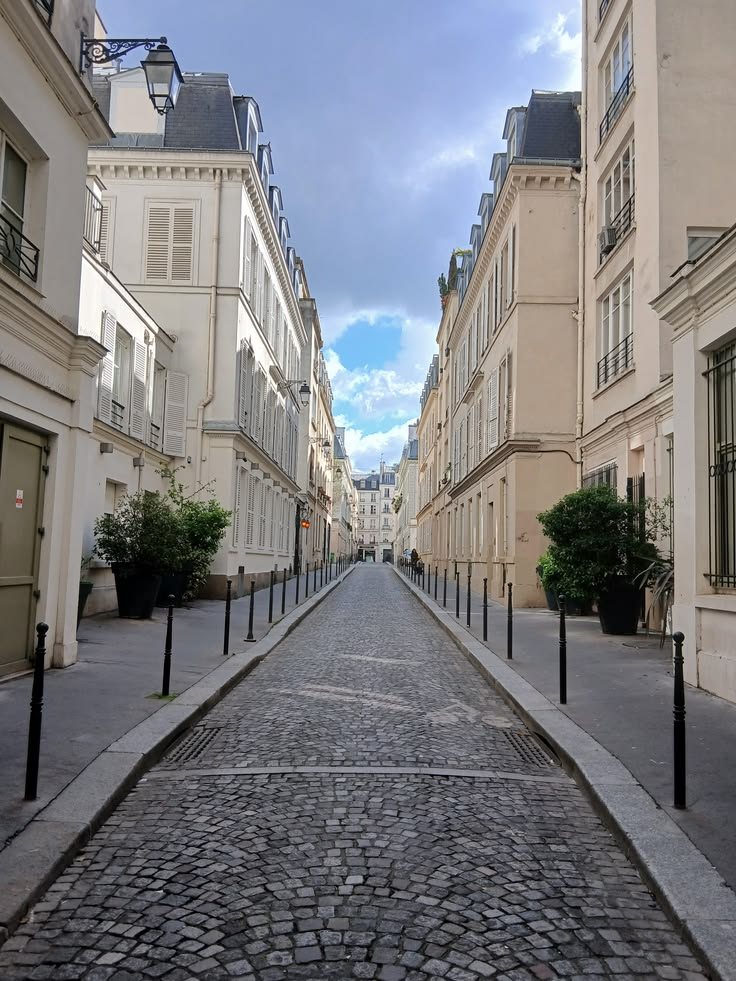 Une rue pavée parisienne sous un ciel nuageux